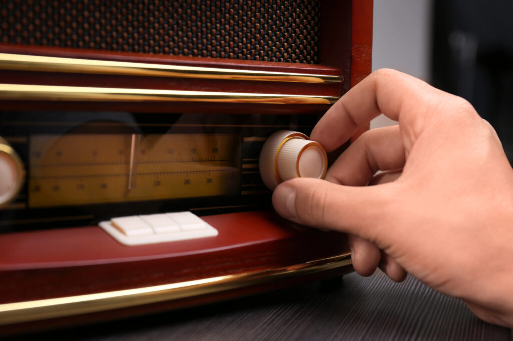 Hand adjusts old fashioned radio dial.
